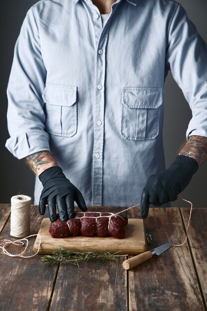 Butcher ties meat with rope to smoke , on table with species