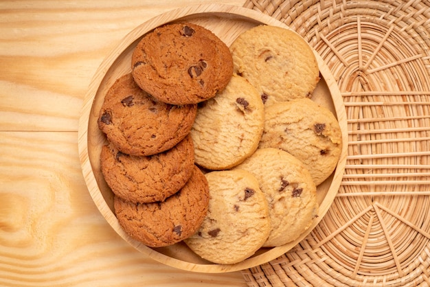 木製の背景に木製プレートのバタークッキーチョコレートチップクッキーを提供する準備ができて
