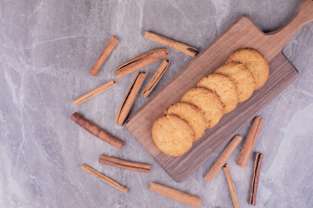 Butter cookies with cinnamon sticks on wooden platter.