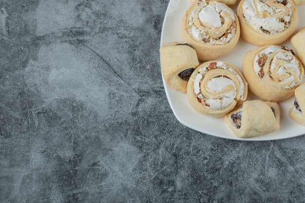 Butter cookies with sugar powder in a white ceramic plate.