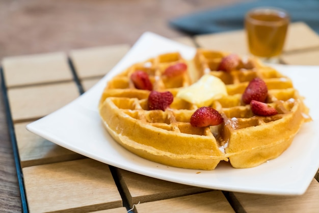 Free photo butter waffle with honey and strawberry