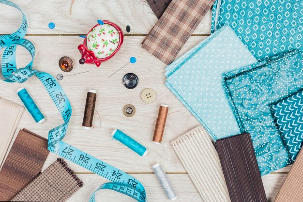 Buttons; a set of needles; thread reels are needed for sewing clothes on wooden table