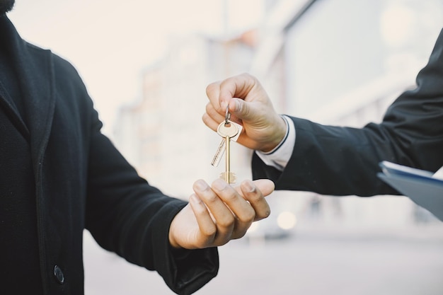 Buying property concept. Man in uniform giving the keys to black man