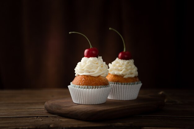 C shloseupot of delicious cupcakes with cream and cherries on top