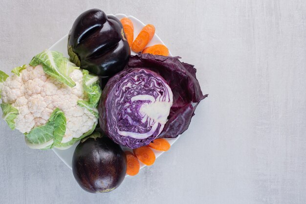 Cabbage, cauliflower, eggplants on white plate. High quality photo