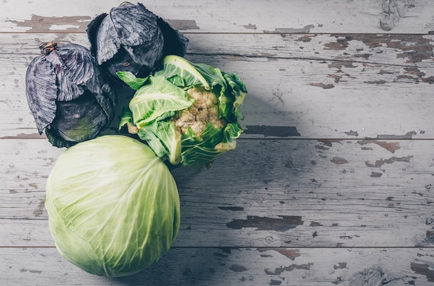 Free photo cabbage with cauliflower and red cabbage top view on a white wooden background