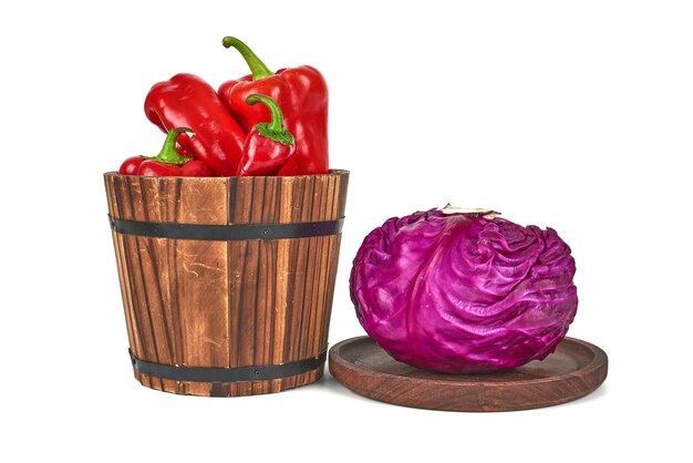 Cabbage on a wooden platter and peppers in a bucket.