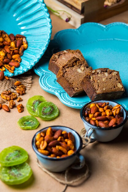Cacao walnut bread in turquoise plate served with dried kiwi fruit and nuts
