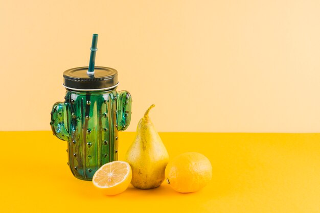 Cactus shape jar with pears and lemons on yellow background