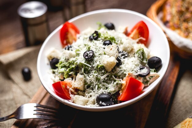 Caesar salad bowl garnished with grated cheese and olive