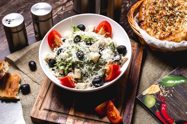 Caesar salad bowl garnished with grated cheese and olive