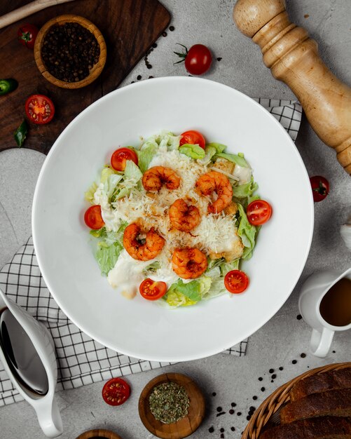 caesar salad topped with fried shrimps