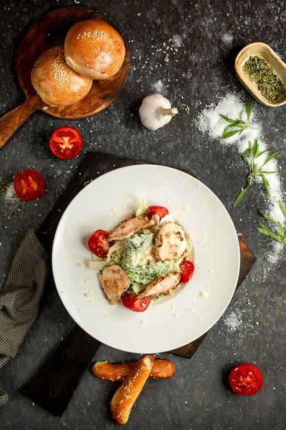 Free photo caesar salad with chicken on a wooden board