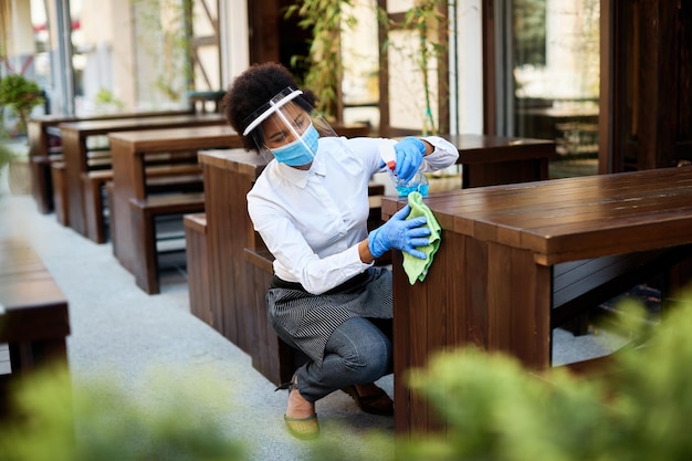 Free photo cafe owner cleaning tables with disinfectant while reopening during covid19 pandemic