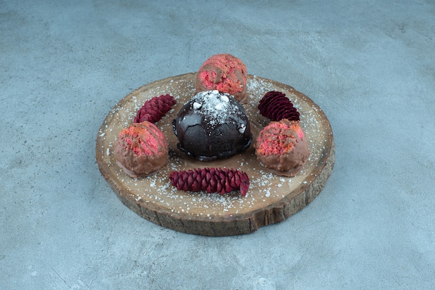 Free photo cake, cookies and pine cones on a board on marble.