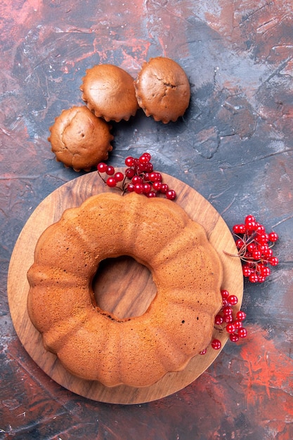 Foto gratuita torta cupcakes gustosa torta con ribes rosso sul tagliere e tre cupcakes