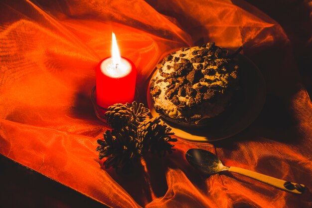 Cake; lit candle and pinecones with spoon on red clothes