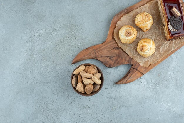 Cake and pastries on wooden board with nuts.