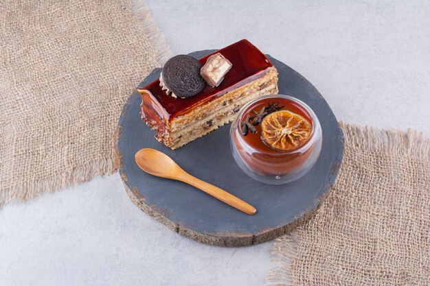 Cake slice, glass of tea and spoon on dark board. High quality photo