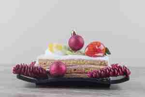 Бесплатное фото Кусочек торта на блюде, украшенном праздничными украшениями на мраморе
