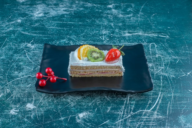 Бесплатное фото Кусочек торта с фруктовой начинкой на блюде на синем фоне. фото высокого качества