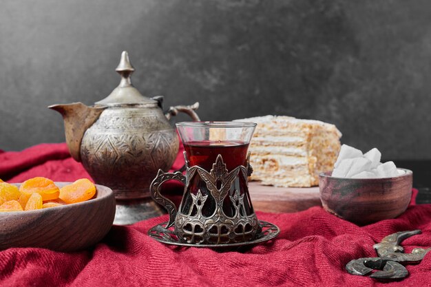 Cake slices and confiture on red towel with tea.