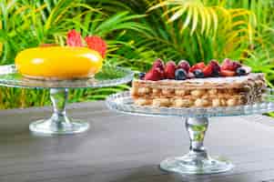 Free photo cake stands with creative desserts against tropical background