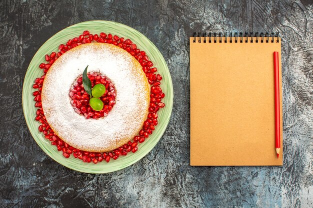 cake with berries a cake with pomegranate and limes next to the notebook pencil