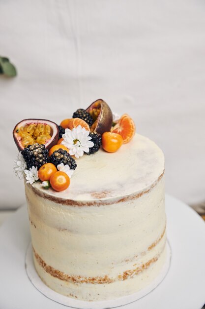 Cake with berries and passionfruits behind a white