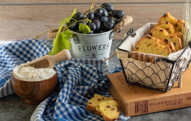 Cake with raisins, flour and grapes on marble table with book