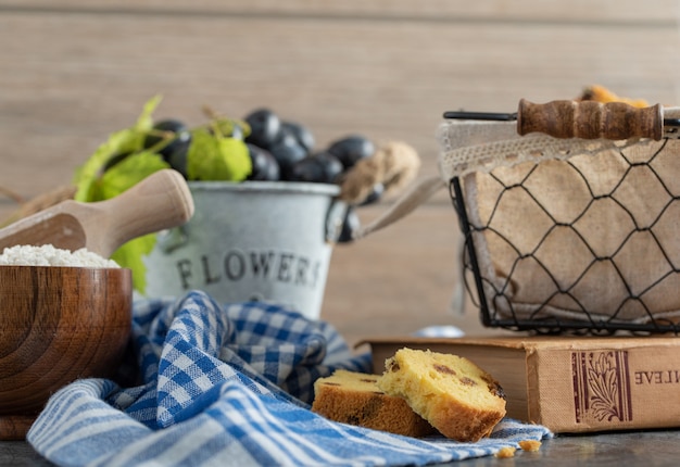 Cake with raisins, flour and grapes on marble table with book