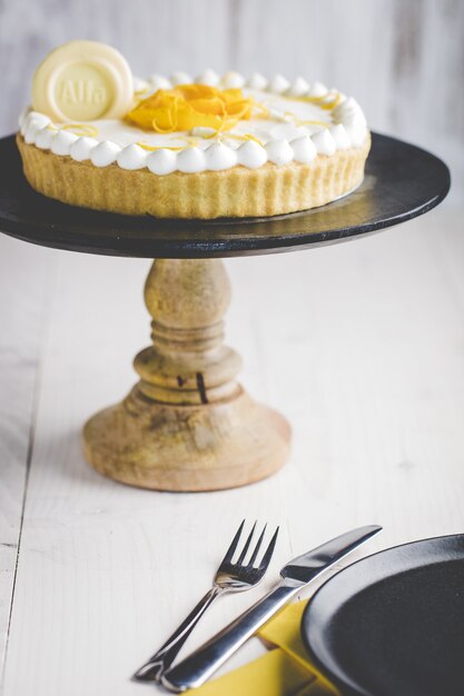 cake on wooden stand and cutlery on the table