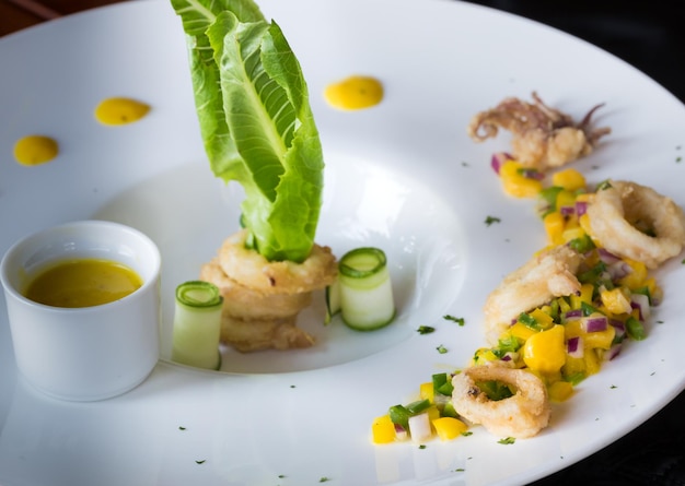 Calamari with mango sauce with nice decoration on white plate