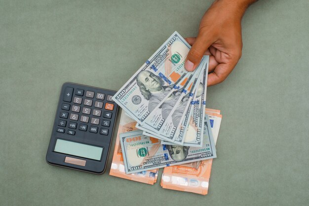 calculator, banknotes on green grey table and man holding dollar bills.