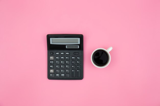 Калькулятор и чашка кофе на розовом фоне