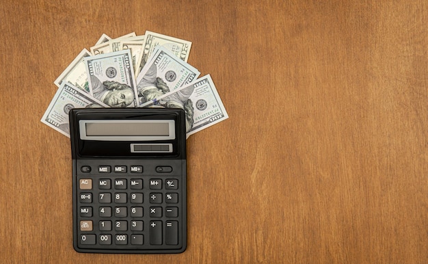 Free photo calculator and dollar bills on an wooden background flat lay