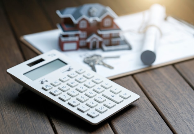 a calculator in front of a Villa house model with a blueprint