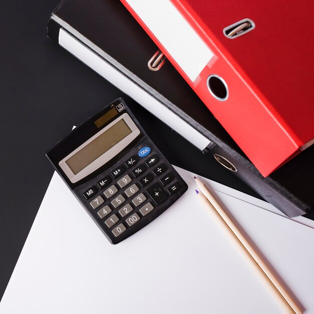 Калькулятор; карандаши; бумажные и бумажные файлы на черном фоне