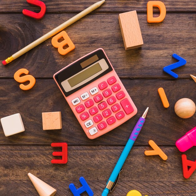 Calculator and stationery amidst letters and geometric figures