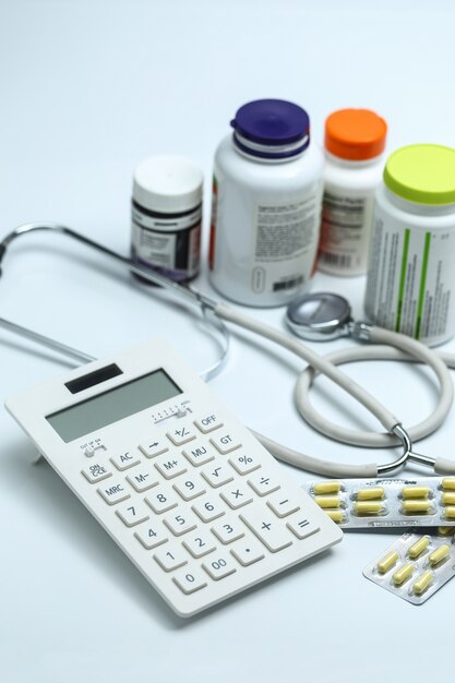 Free photo calculator, stethoscope and medicine bottles on white background