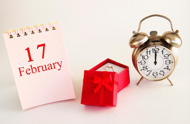 2월 17일 반지와 알람 시계가 있는 빨간색 선물 상자가 있는 밝은 배경의 달력 날짜