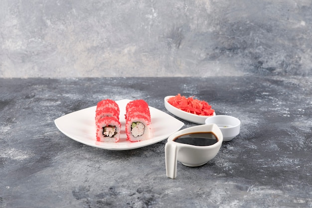 Foto gratuita involtini californiani con caviale di pesce volante su piatto bianco con zenzero e wasabi