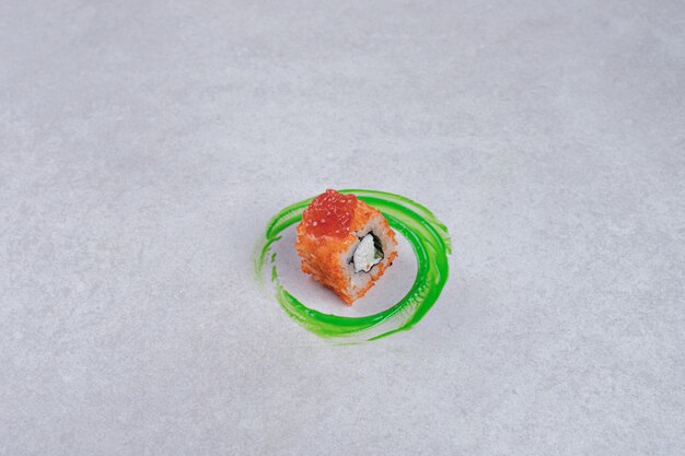 California sushi roll on white background with green plastic ring.