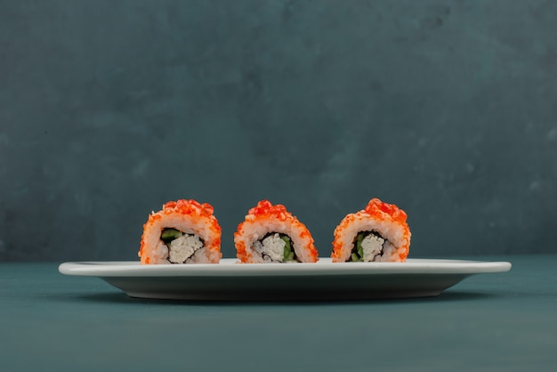 Foto gratuita rotolo di sushi della california con caviale sul tavolo blu.