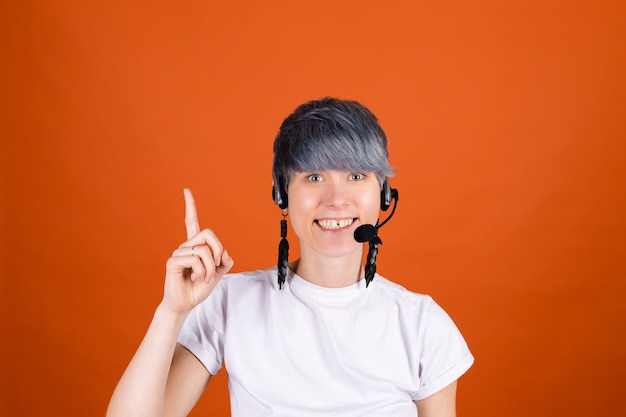 Free photo call center assistant with headphones on orange wall look happy and positive with confident smile point finger up