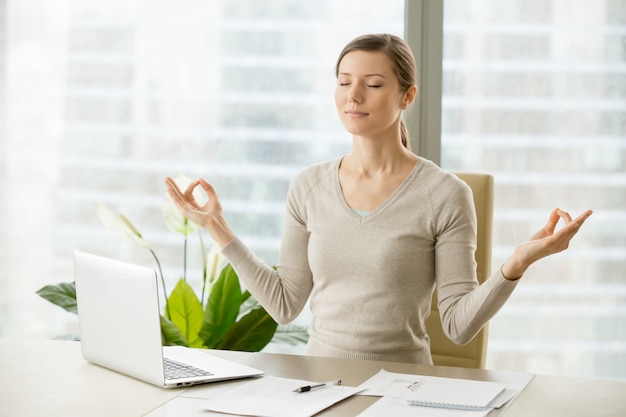 Calm businesswoman relaxing with breath gymnastics