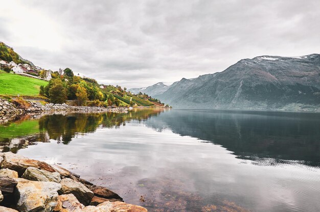 Calm lake at Norwegian national park surrounded with big mountains and gloomy weather.