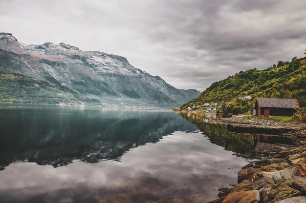 Calm lake at Norwegian national park surrounded with big mountains and gloomy weather.