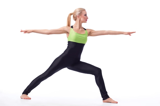 Calma e pace. studio shot di una donna sana e in forma che fa yoga in piedi in una posizione di guerriero che si esercita isolato su copyspace bianco