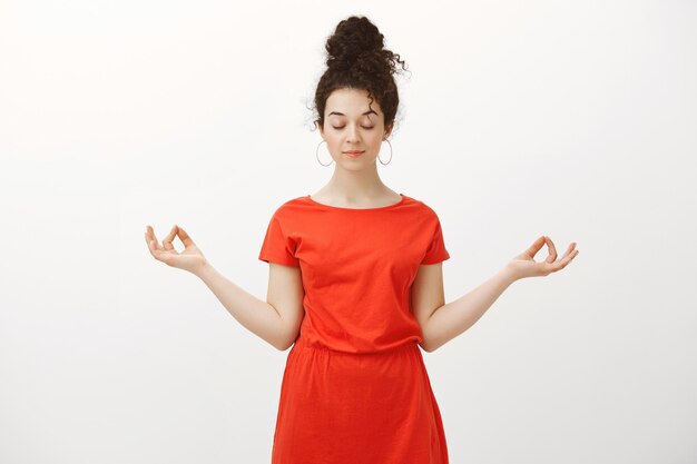 calm relaxed feminine woman with curly hair combed in bun hairstyle